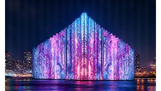 A large building facade illuminated by intricate, colorful projection mapping, creating mesmerizing abstract patterns at a night event.